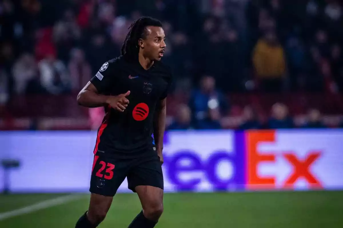 Jugador de fútbol corriendo en el campo durante un partido con uniforme negro y número 23.