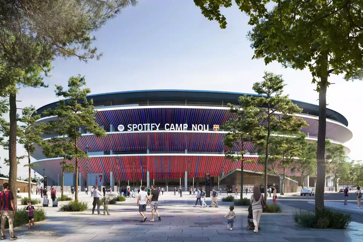 Vista frontal del estadio Spotify Camp Nou con personas caminando en la entrada y árboles alrededor.
