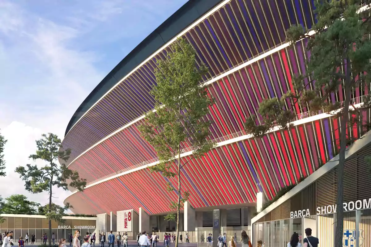 Vista exterior de un estadio moderno con paneles de colores rojo y azul y personas caminando alrededor.