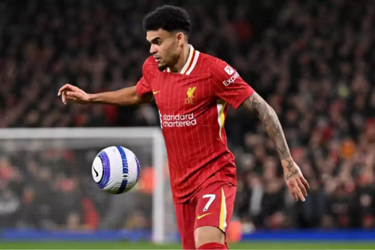 Soccer player in a red uniform controlling a ball during a match in a stadium full of spectators Soccer player in a red uniform controlling a ball during a match in a stadium full of spectators