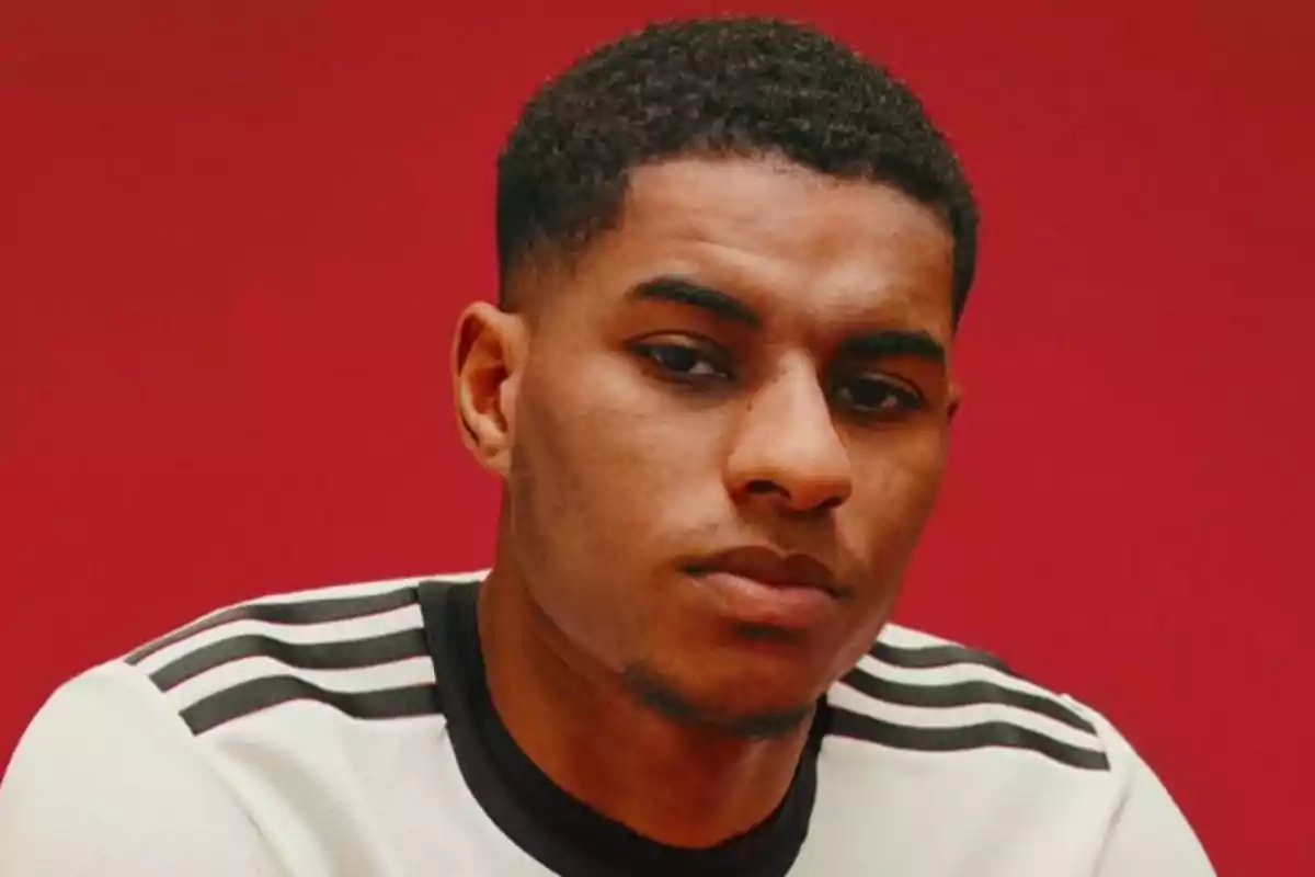 Young man in a white jersey with black stripes posing in front of a red background Young man in a white jersey with black stripes posing in front of a red background