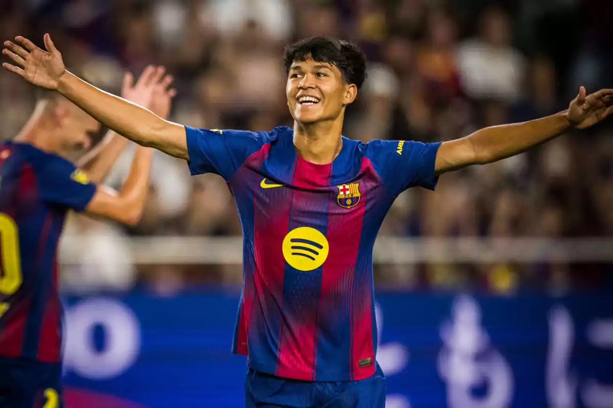 Barcelona player celebrating a goal with arms outstretched and a big smile on his face during a soccer match