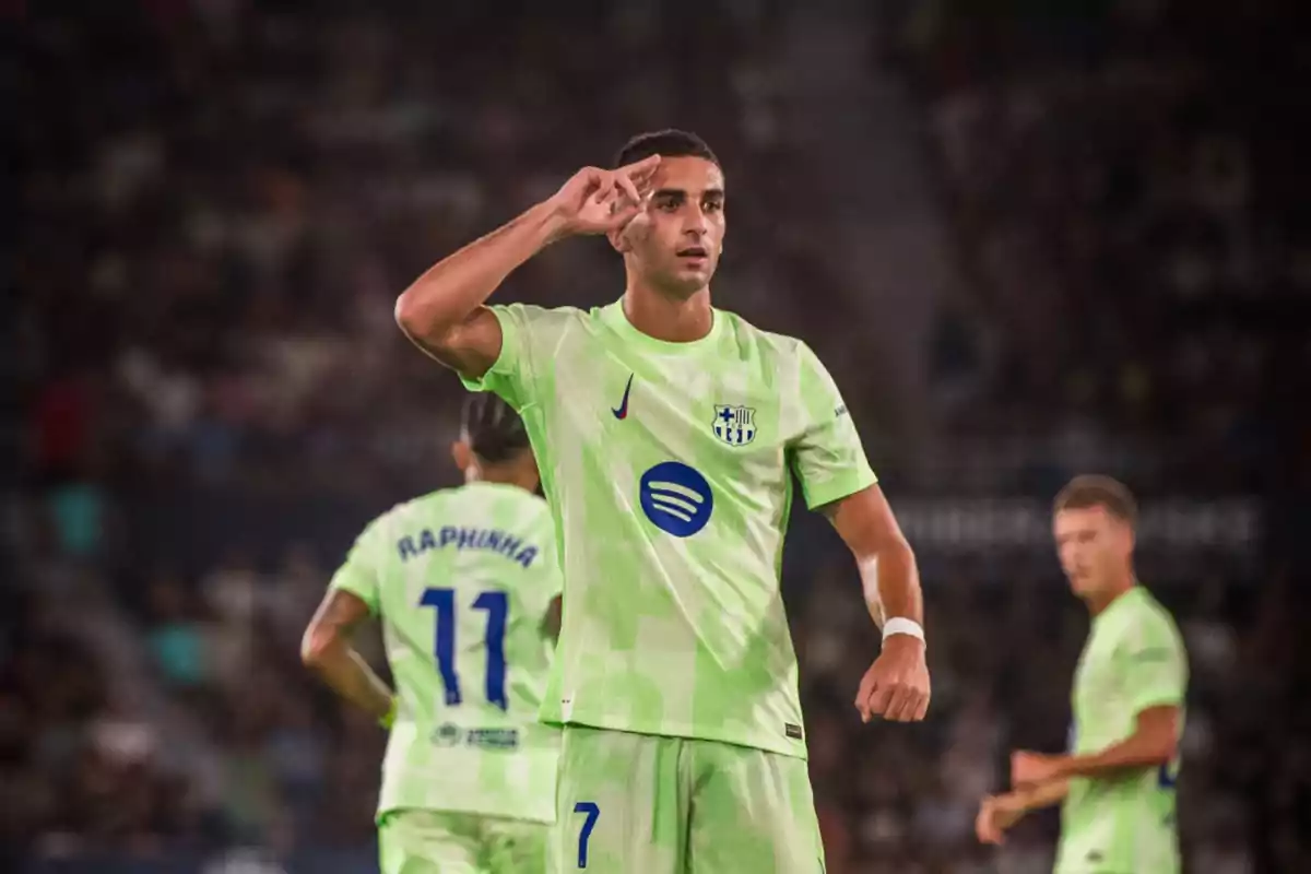 Futbolista del Barcelona celebrando un gol con la mano en la frente mientras usa el uniforme alternativo verde fosforescente Futbolista del Barcelona celebrando un gol con la mano en la frente mientras usa el uniforme alternativo verde fosforescente