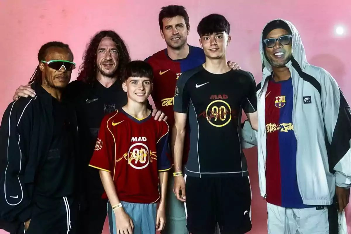 A group of people poses smiling, wearing sportswear and Barcelona jerseys in front of a pink background.