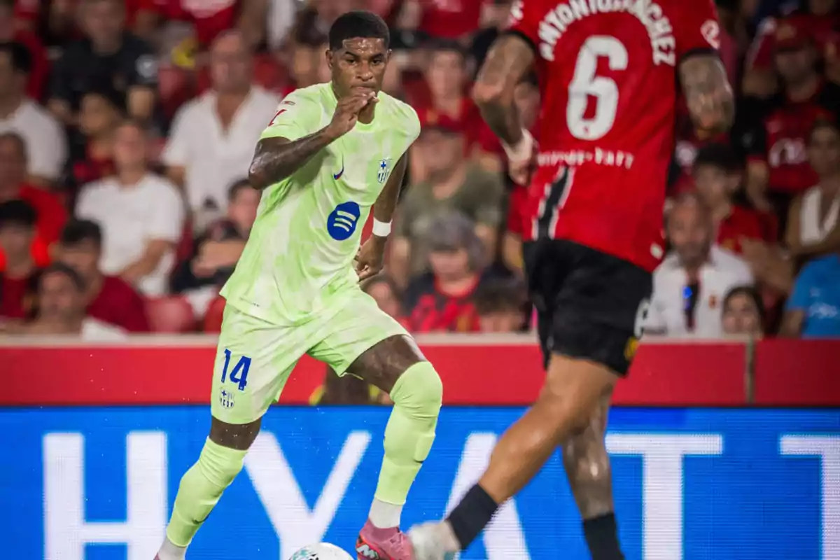 Player in a light green Barcelona uniform advances with the ball while an opponent in a red and black jersey tries to defend during a soccer match. Player in a light green Barcelona uniform advances with the ball while an opponent in a red and black jersey tries to defend during a soccer match.