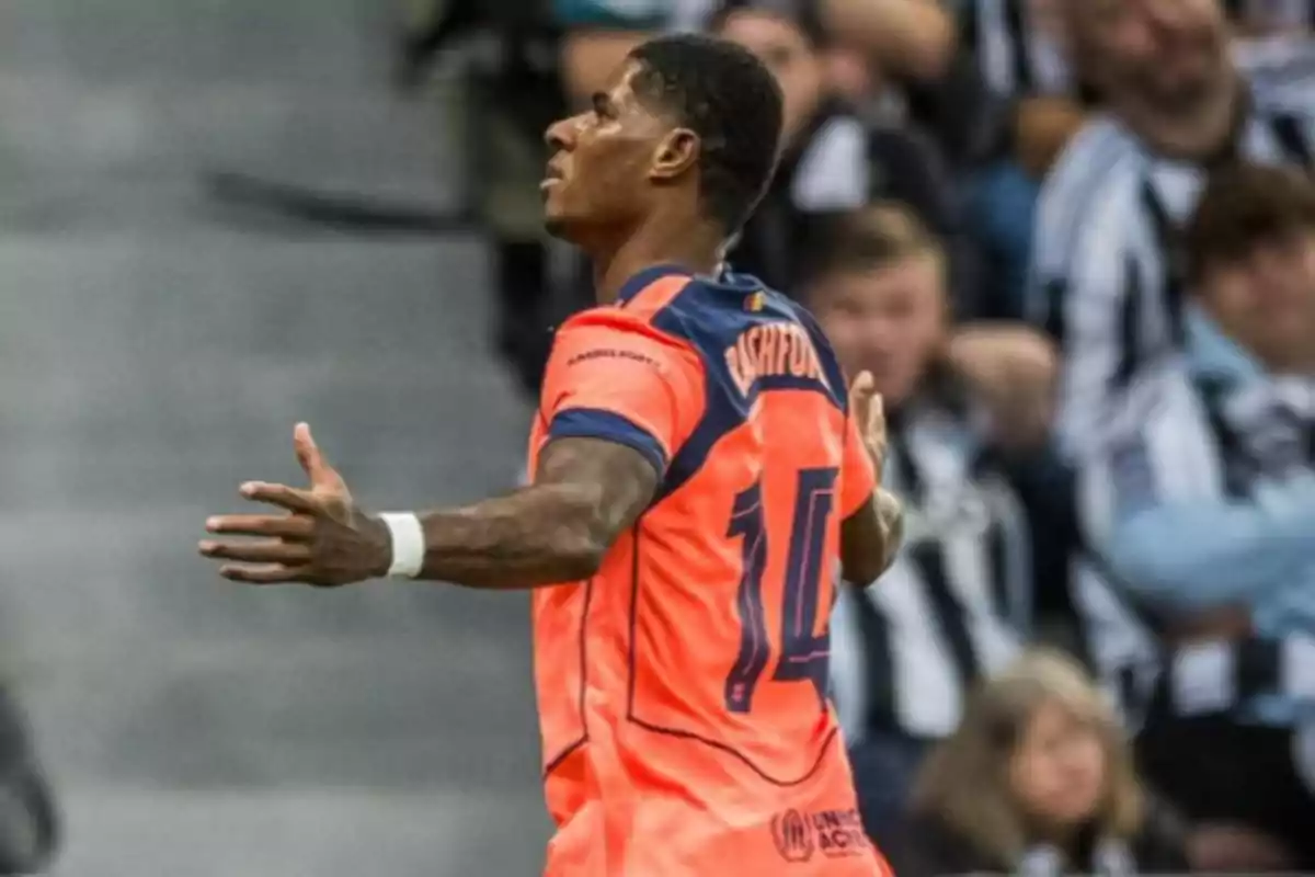 Futbolista con uniforme naranja celebrando un gol frente a una multitud en el estadio