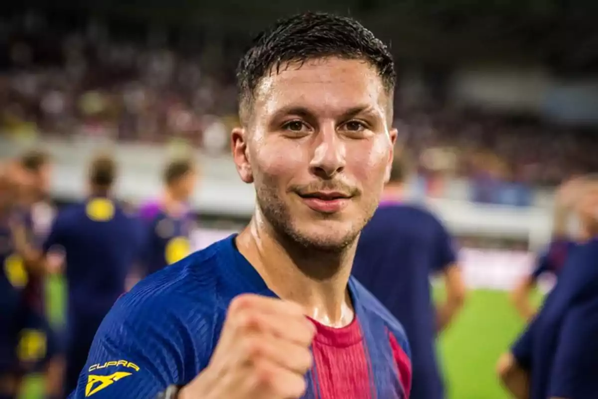 Futbolista celebrando en el campo con el puño en alto y camiseta azul y roja Futbolista celebrando en el campo con el puño en alto y camiseta azul y roja