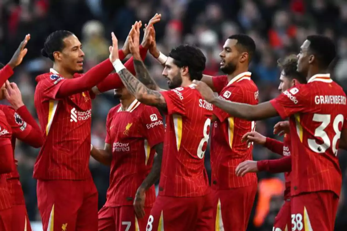 Jugadores de fútbol del Liverpool celebran juntos en el campo con uniformes rojos