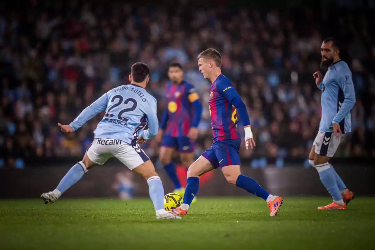 Jugadores de fútbol disputan el balón durante un partido entre equipos con uniformes azul celeste y azul con rojo en un estadio lleno de espectadores Jugadores de fútbol disputan el balón durante un partido entre equipos con uniformes azul celeste y azul con rojo en un estadio lleno de espectadores