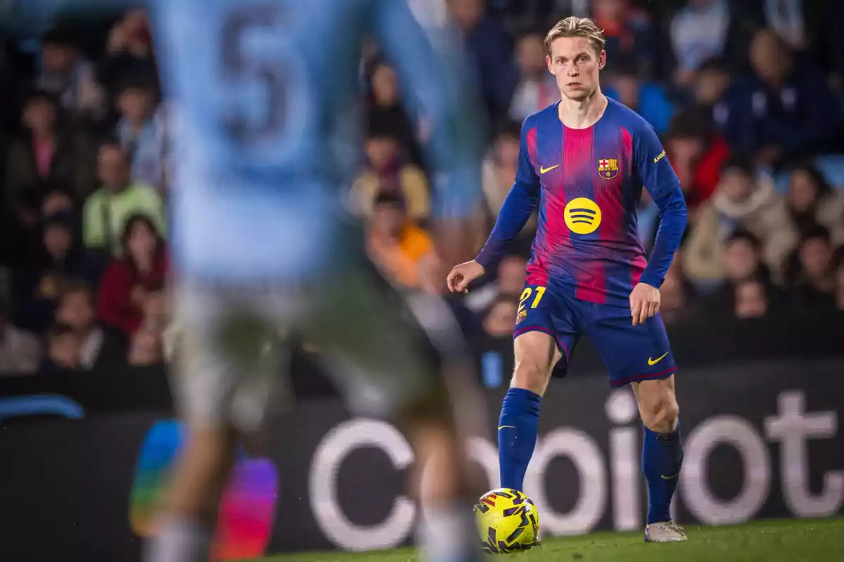 Futbolista del Barcelona controlando el balón durante un partido con un jugador rival desenfocado en primer plano y público en las gradas de fondo Futbolista del Barcelona controlando el balón durante un partido con un jugador rival desenfocado en primer plano y público en las gradas de fondo