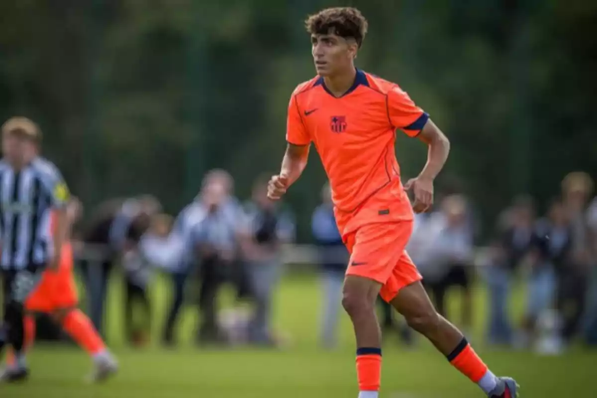 Joven futbolista con uniforme naranja corriendo en un campo de fútbol durante un partido Joven futbolista con uniforme naranja corriendo en un campo de fútbol durante un partido