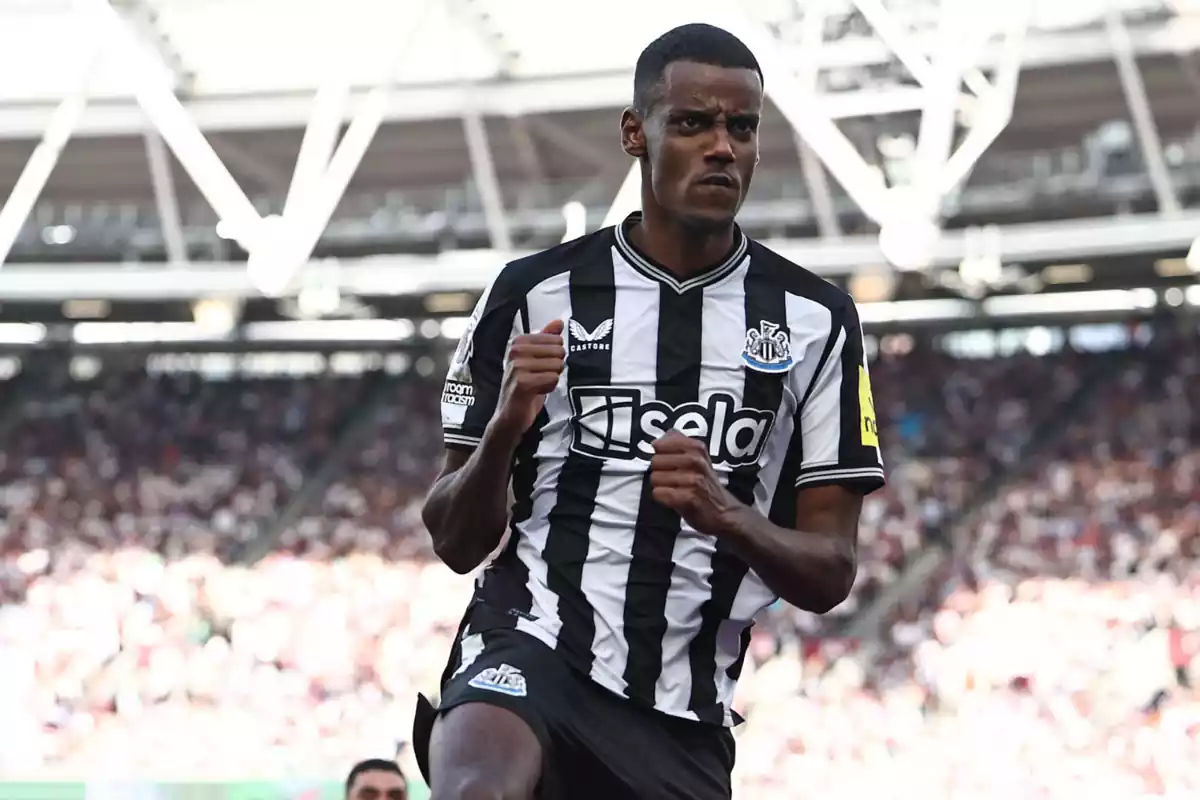 Alexander Isak celebra un gol con los puños cerrados con la equipación negra con rallas blancas del Newcastle United