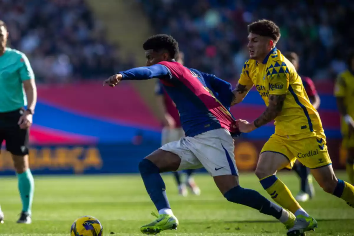 Two soccer players compete for the ball on the field while one of them grabs the other's jersey.