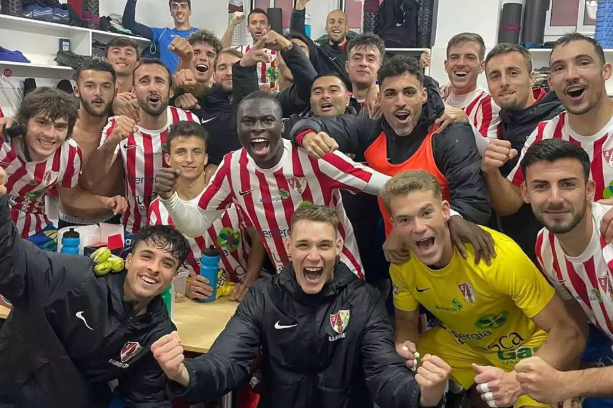 Un equipo de futbol de Barbastro tomándose una foto dentro de un vestuario celebrando