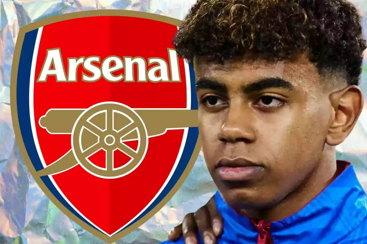 A young man in a blue jacket is in front of the Arsenal crest.