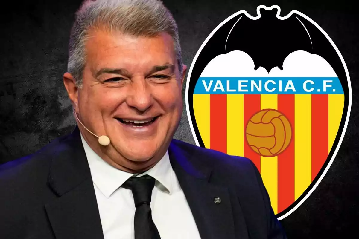 Un hombre sonriente con un micrófono en la oreja frente al escudo del Valencia C.F.