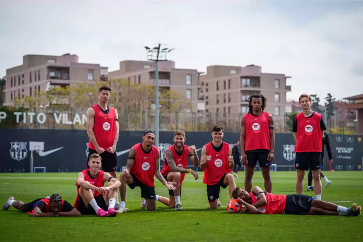 Un grupo de jugadores de fútbol con petos rojos posando en un campo de entrenamiento. Un grupo de jugadores de fútbol con petos rojos posando en un campo de entrenamiento.