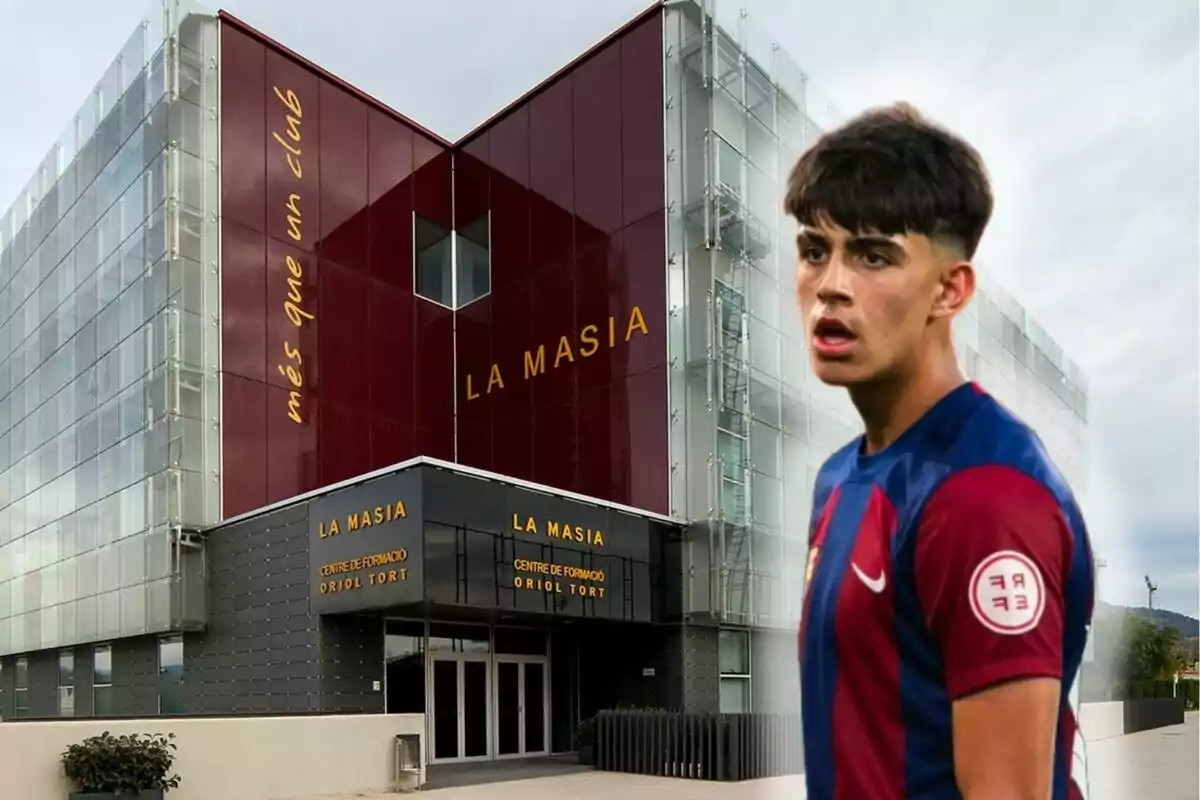 Un jugador de fútbol con uniforme azul y rojo frente al edificio de La Masia, centro de formación del FC Barcelona.