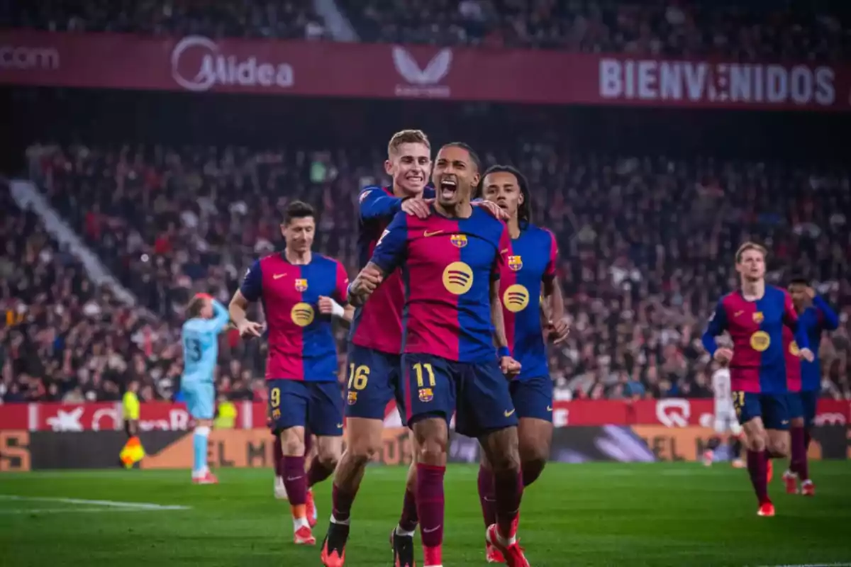 Soccer players celebrating a goal in a stadium full of spectators.