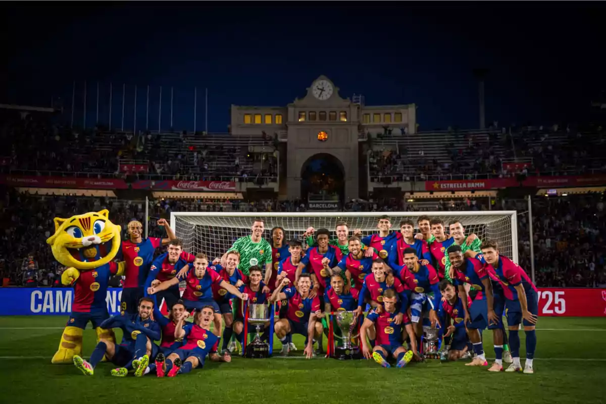 A soccer team poses with trophies in front of a goal in a stadium full of spectators, accompanied by a mascot dressed as a tiger.