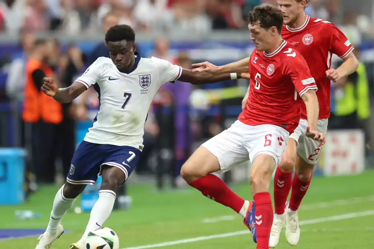 Jugadores de fútbol de los equipos de Inglaterra y Dinamarca disputando el balón en un partido.