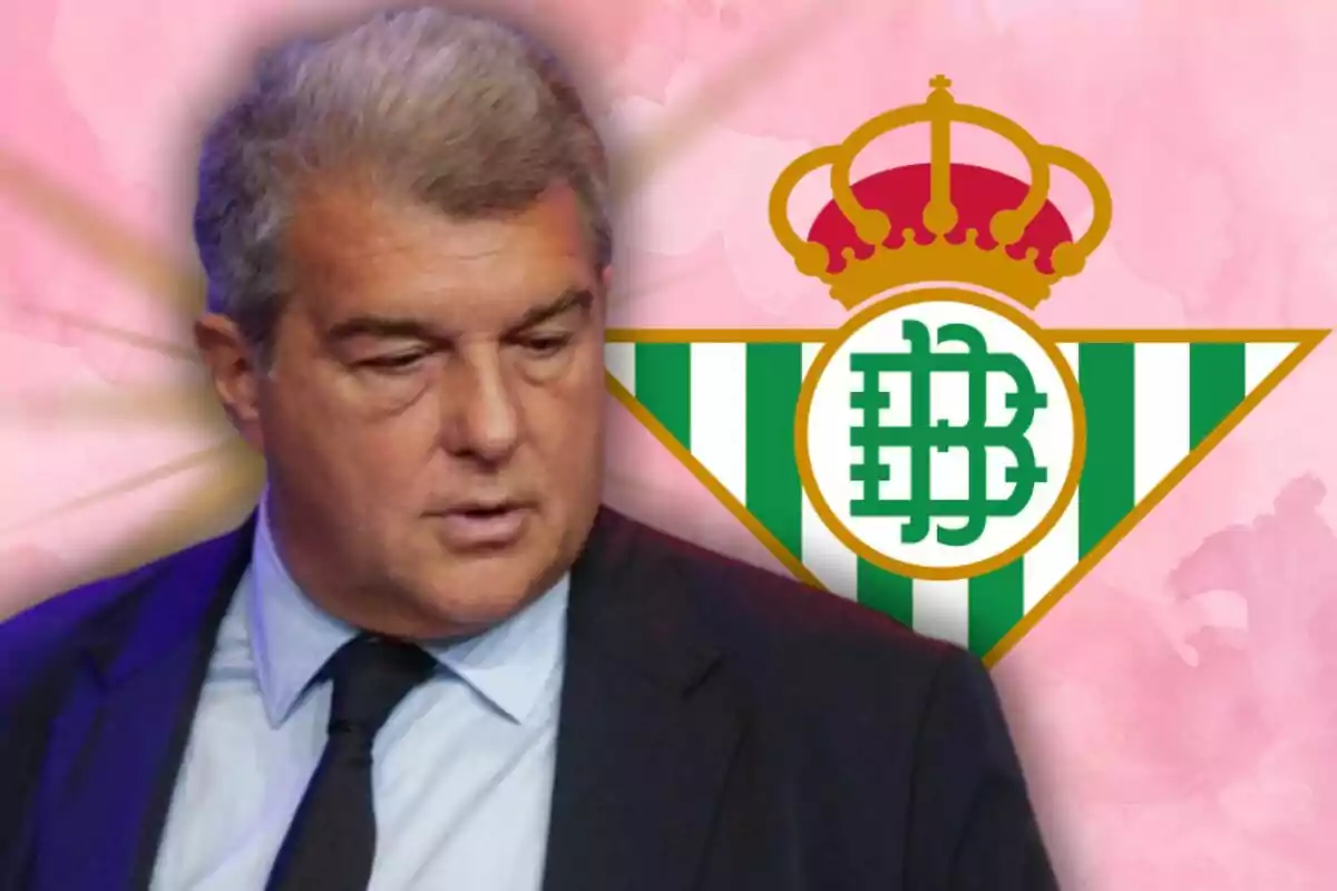 Un hombre de cabello canoso y traje oscuro aparece frente al escudo del Real Betis Balompié sobre un fondo rosado.