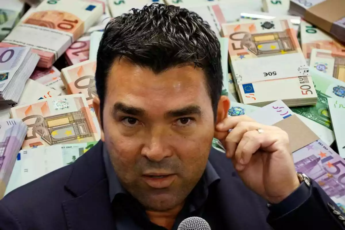 Un hombre con cabello oscuro y expresión seria, sosteniendo un micrófono, con una gran cantidad de billetes de euro en el fondo.