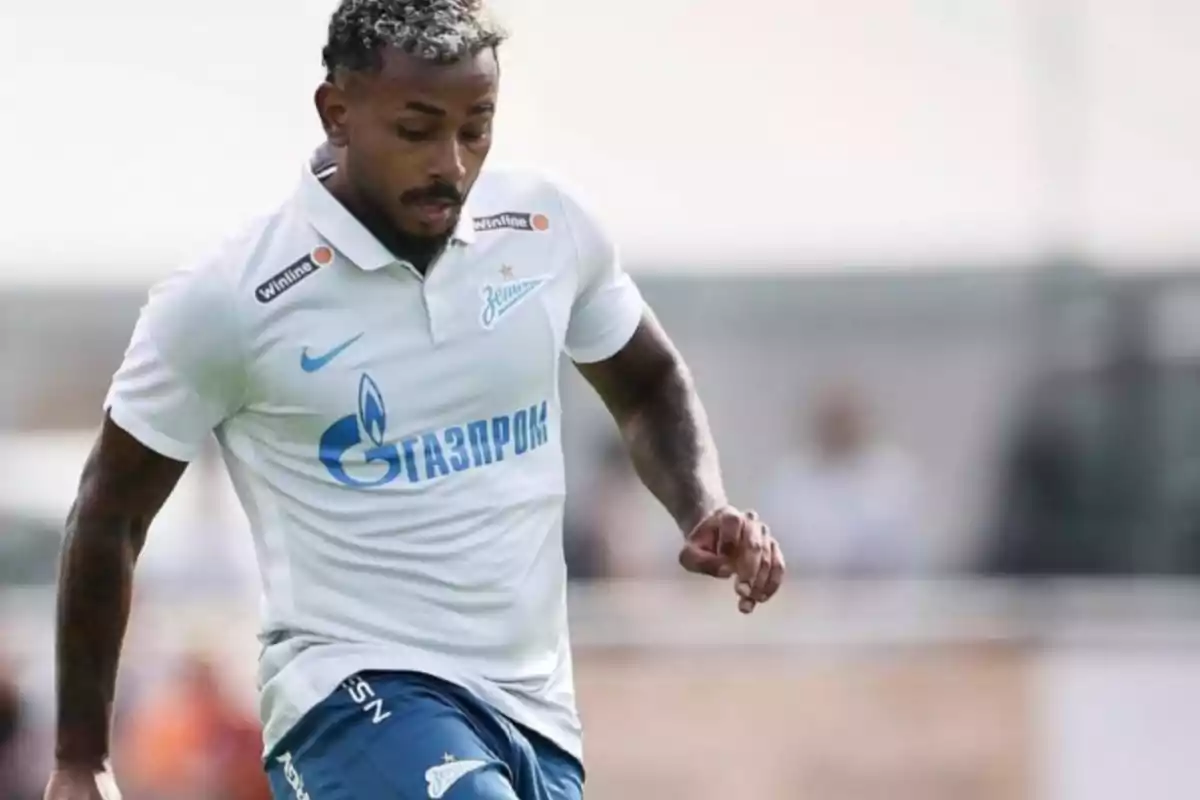 Jugador de fútbol con uniforme blanco y azul en acción durante un partido.