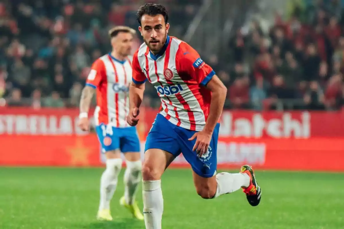 Jugador de fútbol con uniforme rojo y blanco corriendo en el campo durante un partido.