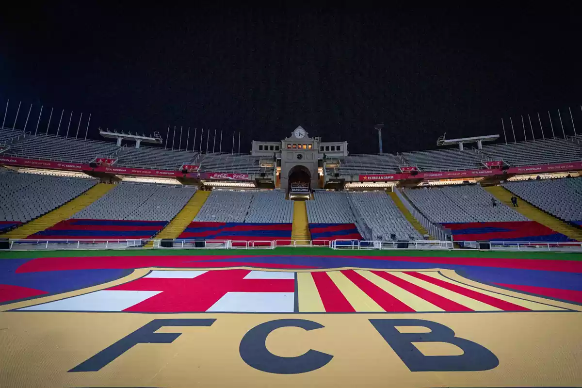 El estadio olimpico Lluís Companys de noche vacío con el escudo del Barça en el césped