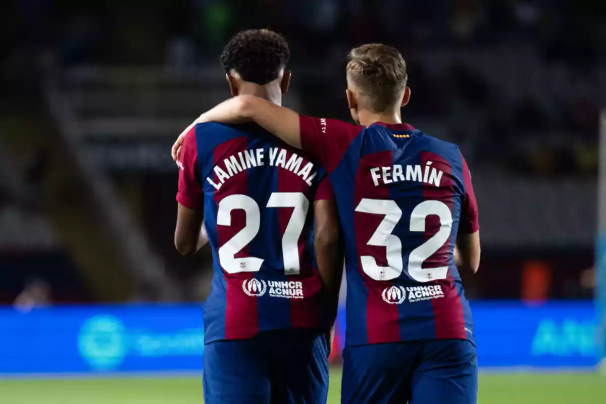 Los jugadores del Barça Lamine Yamal y Fermín López abrazados en el campo, luciendo sus números 27 y 32