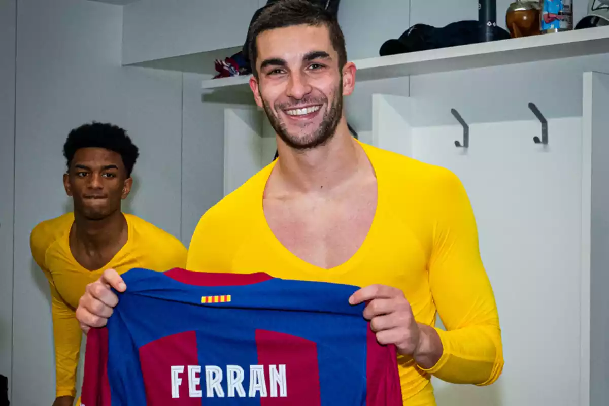 Ferran Torres aguantando y enseñando una camiseta del Barça con su nombre. Está sonriendo