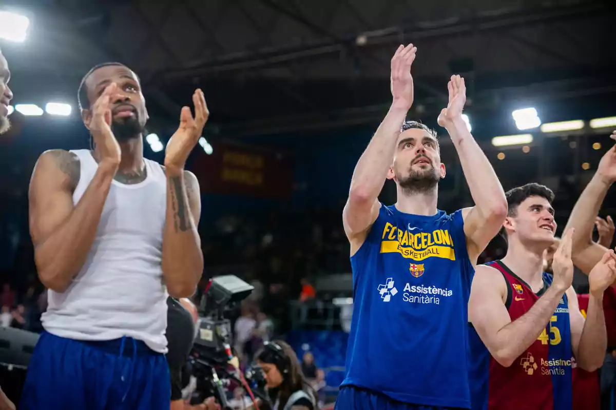 Jugadores de baloncesto aplaudiendo en una cancha después de un partido.