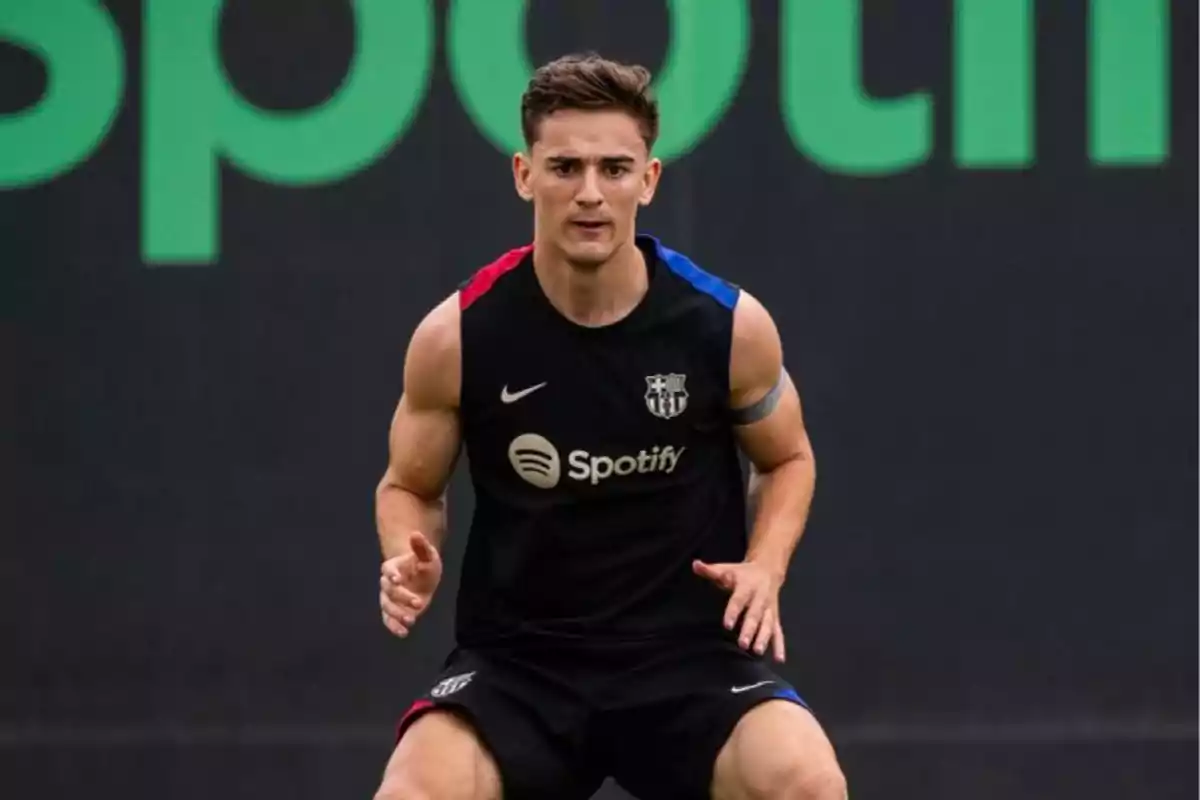 Un jugador de fútbol con uniforme de entrenamiento del FC Barcelona y el logo de Spotify en el pecho, en una postura de ejercicio físico.