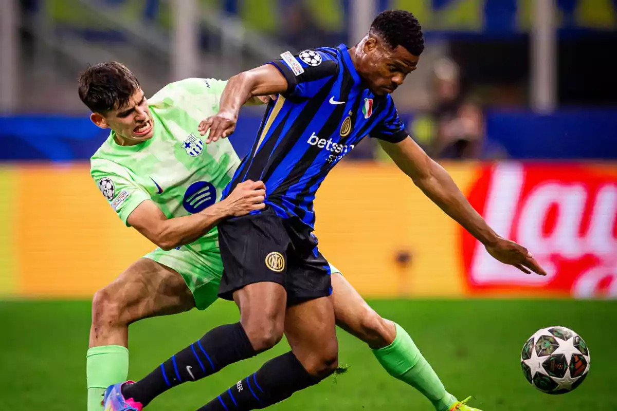 Two players compete for the ball in a match, one wearing a blue and black uniform and the other light green. Two players compete for the ball in a match, one wearing a blue and black uniform and the other light green.