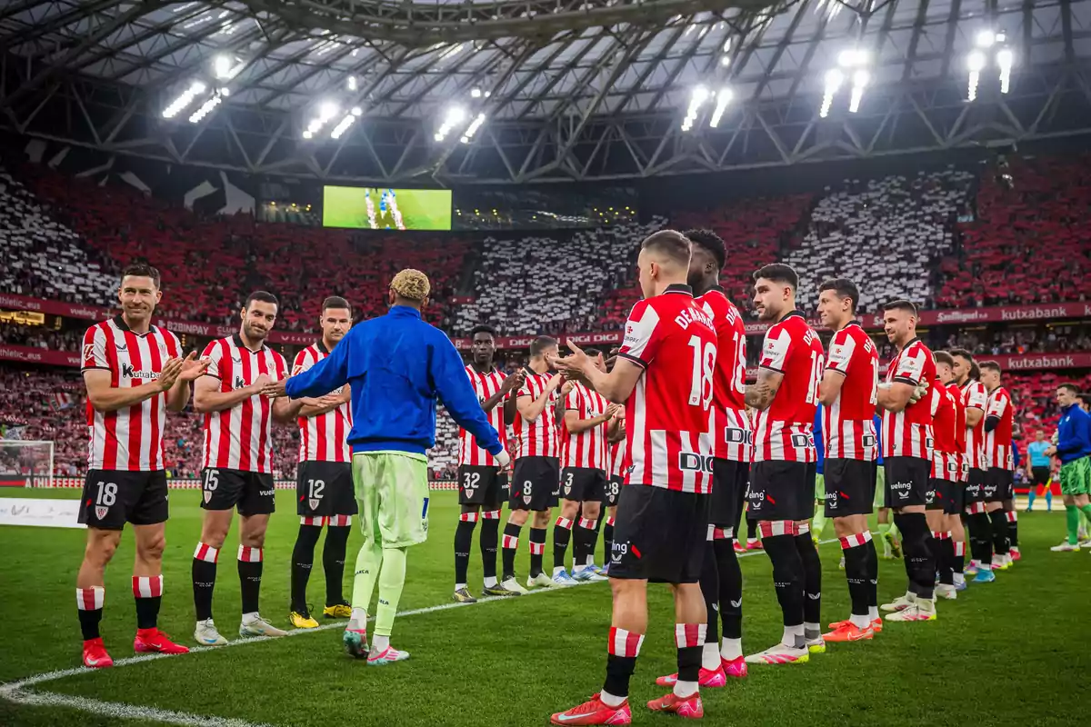 Jugadores de fútbol con uniformes a rayas rojas y blancas forman un pasillo en un estadio lleno de espectadores. Jugadores de fútbol con uniformes a rayas rojas y blancas forman un pasillo en un estadio lleno de espectadores.
