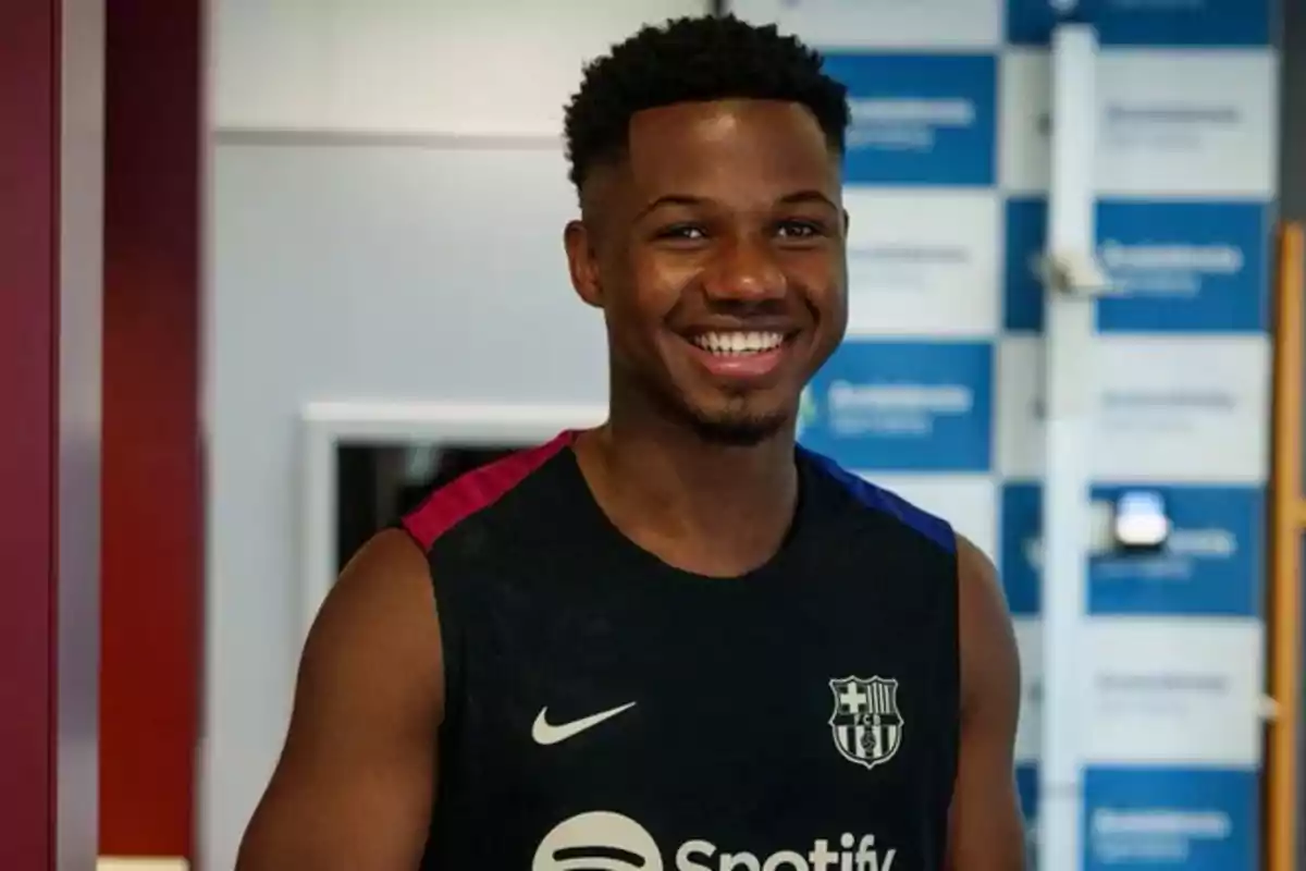 Un jugador de fútbol sonriente con una camiseta de entrenamiento del FC Barcelona.