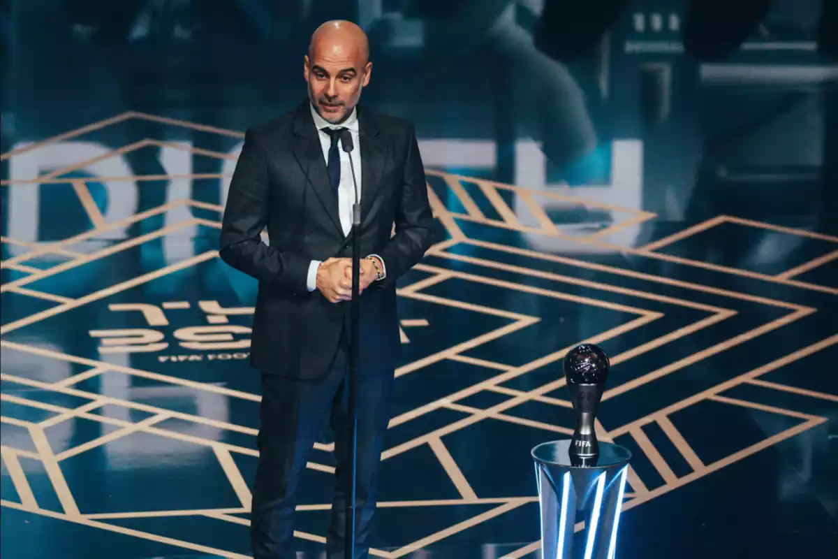 Coach Pep Guardiola, standing on stage at the FIFA The Best gala, receiving an award