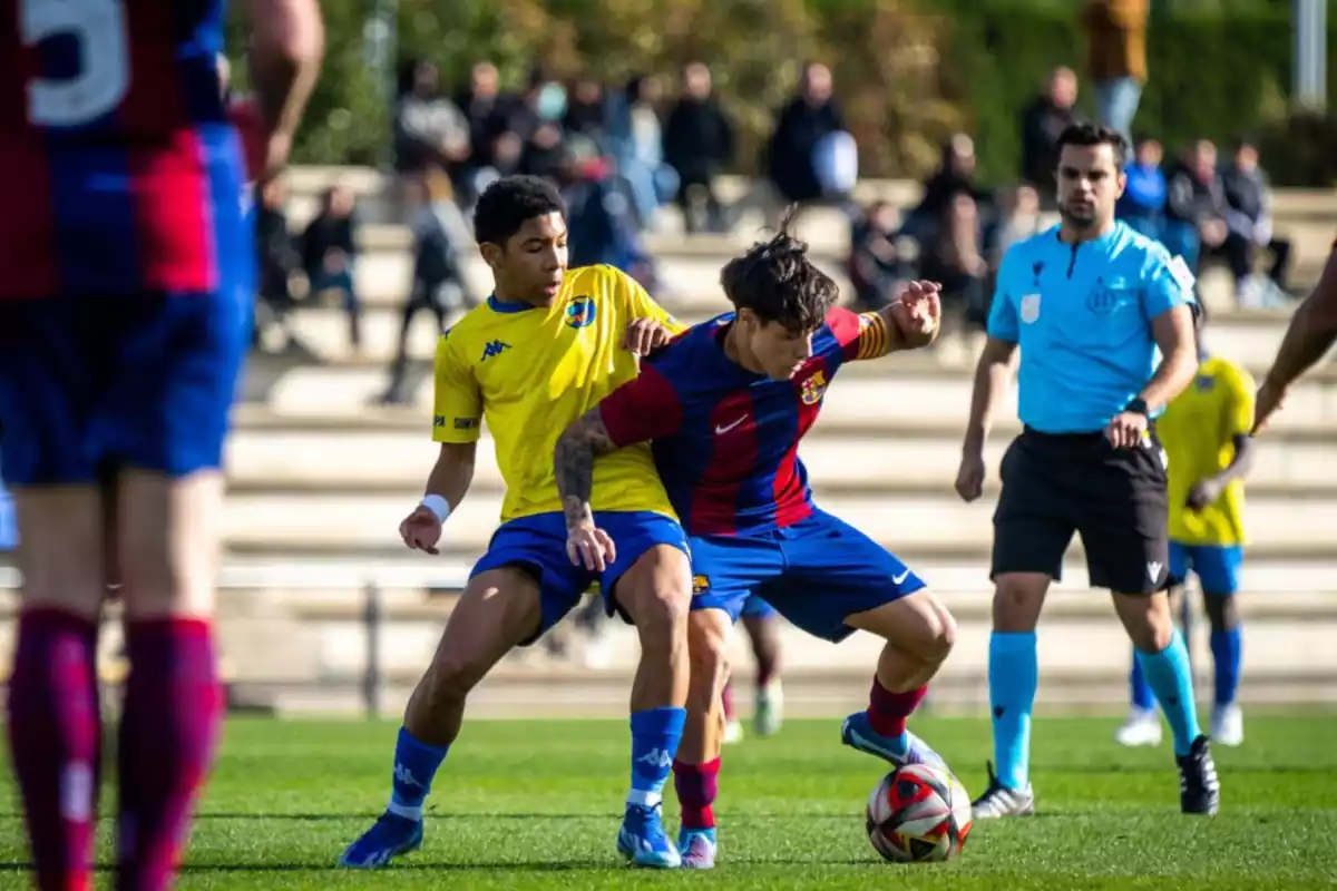 El jugador de la Masia del Barça Guille Fernández disputando un balón con un jugador del equipo rival