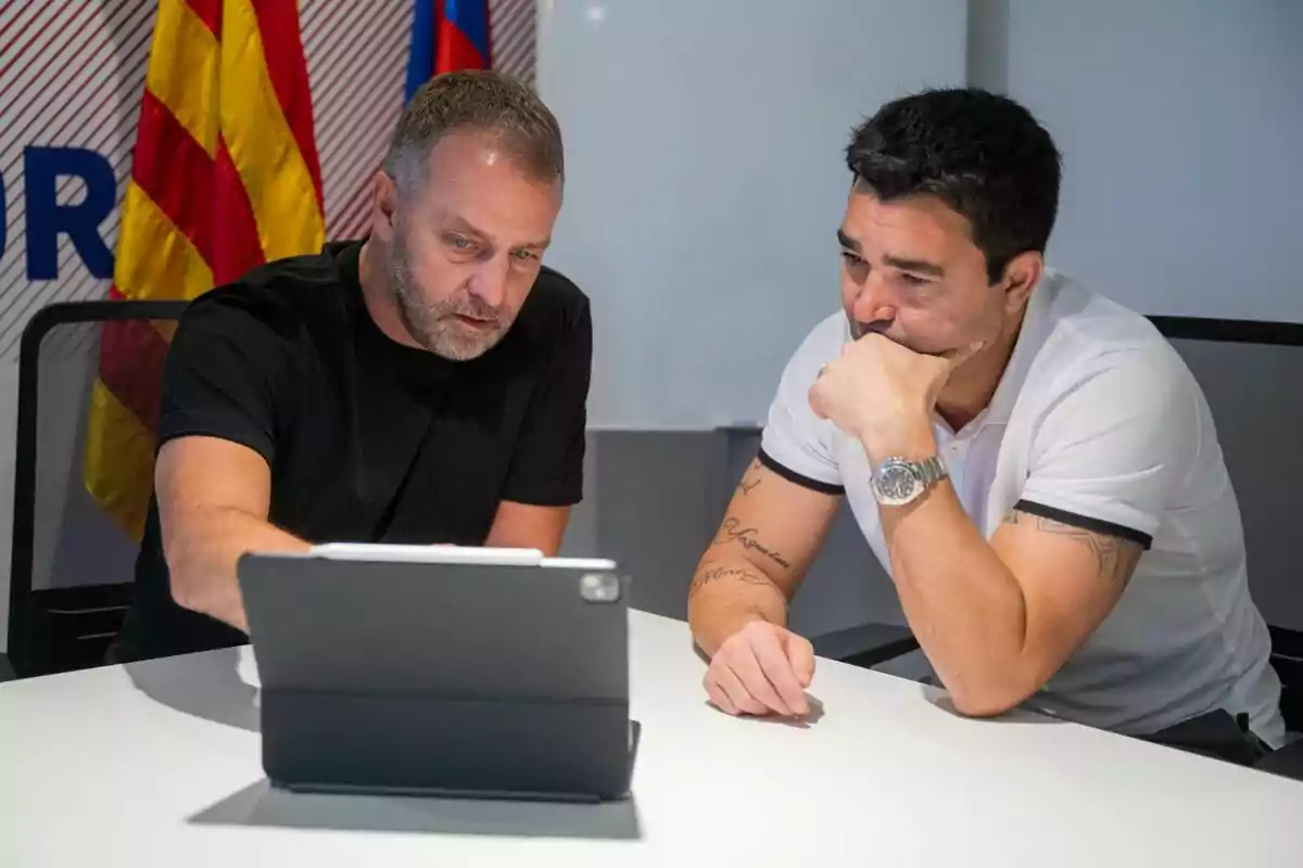 Hansi Flick y Deco sentados en una mesa con una tableta enfrente organizando el trabajo del FC Barcelona