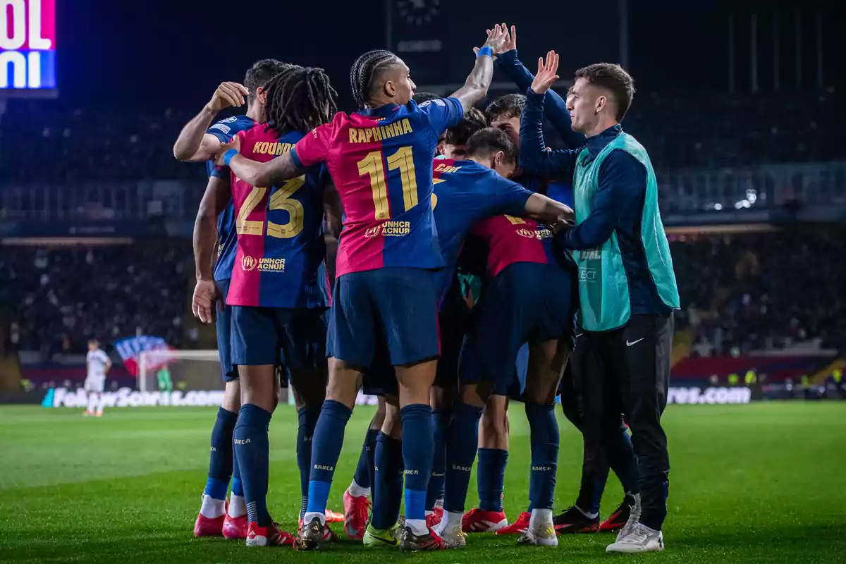 Soccer players celebrating a goal on the field during a night game.