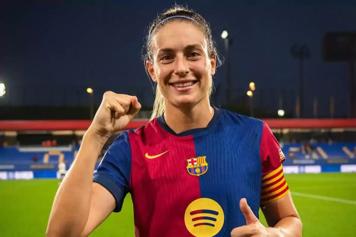 Jugadora de fútbol sonriente con uniforme del FC Barcelona en un estadio.