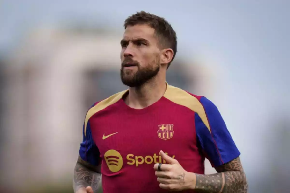 Iñigo Martinez, con la camiseta de entrenamiento roja, azul y amarilla del FC Barcelona, mirando al horizonte