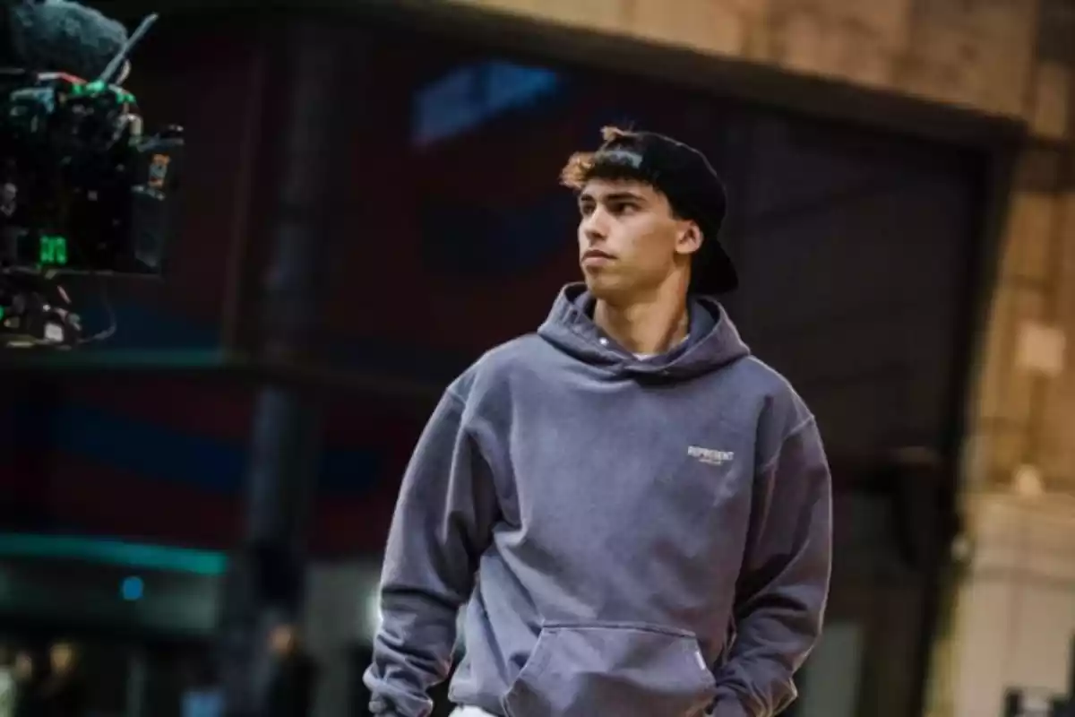 vemos a joao felix vestido con roa de calle, con tonos oscuros y beige, ademas de que lleva una gorra