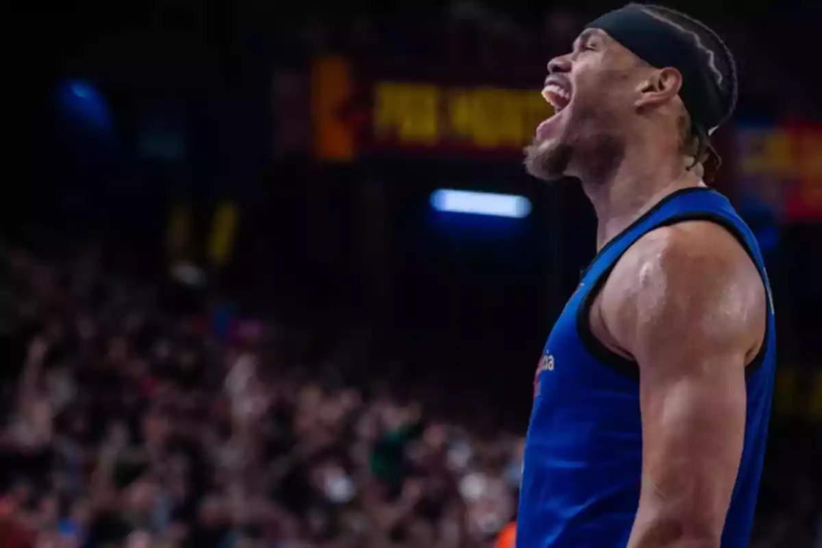 Jugador de baloncesto celebrando en la cancha con el público de fondo.