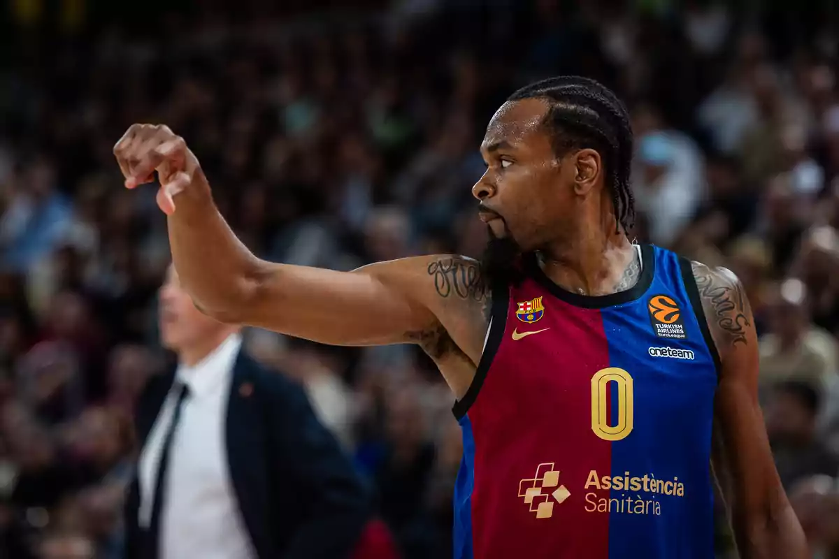 Jugador de baloncesto con uniforme azul y rojo en acción durante un partido.