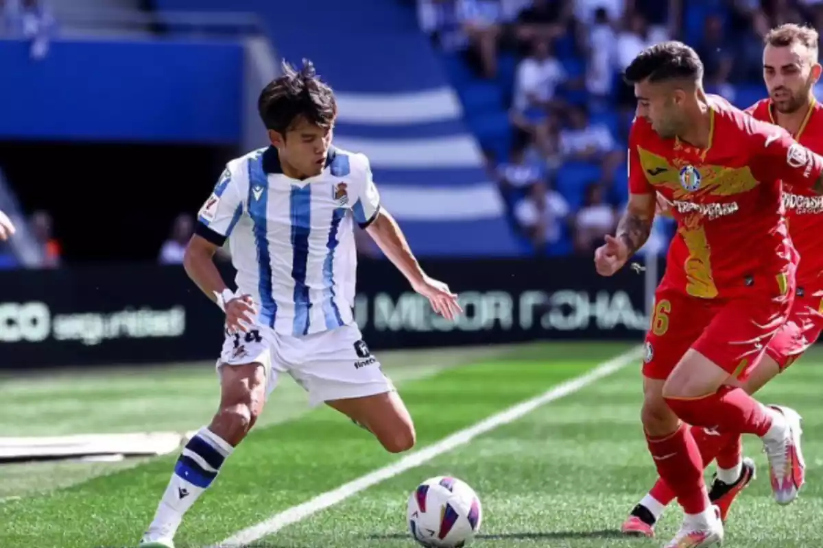 Se puede ver a Takefusa Kubo controlando un balón delante de un jugador del Getafe, con posición de regate
