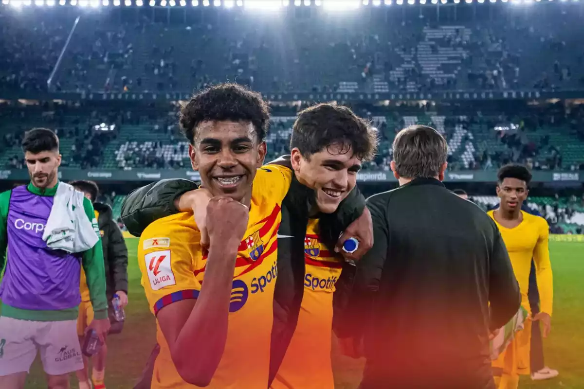 Los jugadores del Barça Lamine Yamal y Pau Cubarsí abrazados y sonriendo, con Lamine levantando el puño