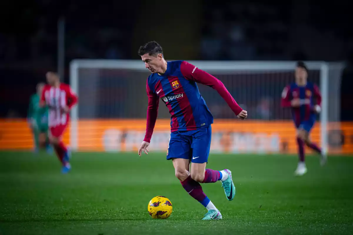 El jugador del Barça Lewandowski conduciendo la pelota en un campo de fútbol