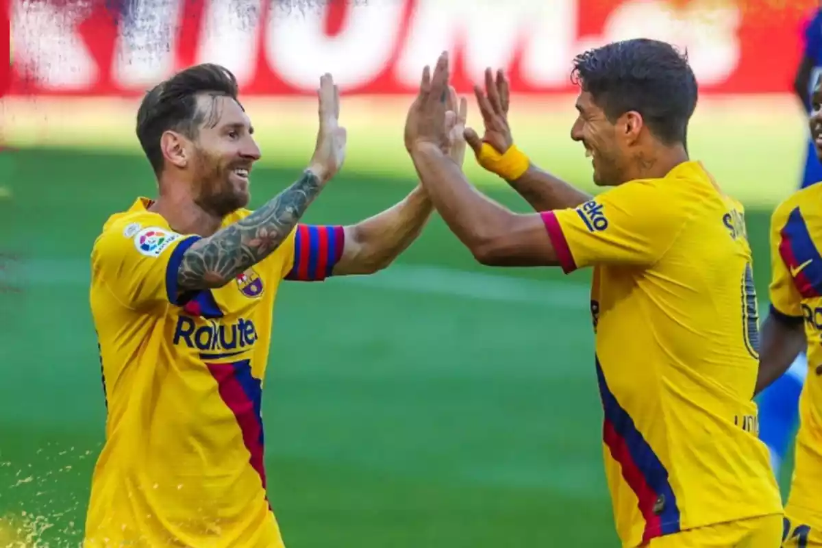 Los jugadores Messi y Suárez celebrando un gol con el Barça chocando sus dos manos juntas y sonriendo